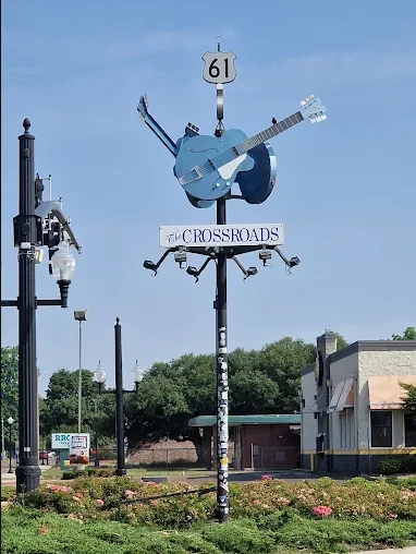 The Blues Crossroads monument at Highways 61 and 49 in Clarksdale, Mississippi — a blue guitar sculpture topped with a Highway 61 shield